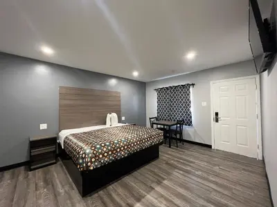 a bedroom with a bed and a table and a door at Sunshine Motel in Long Beach