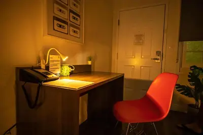 a red chair sitting next to a desk with a phone at Bposhtels Anaheim in Anaheim