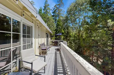 a balcony of a house with chairs and trees at Treetop Cottage in Running Springs