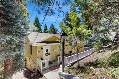 a yellow house with a porch and a street light at Treetop Cottage in Running Springs