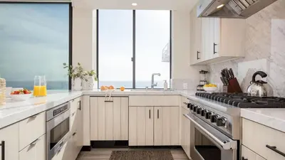a kitchen with white cabinets and a large window at Matador by AvantStay Ocean Front Malibu Pad w Rooftop Patio in Topanga