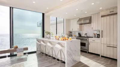 a kitchen with a large window and a counter with stools at Matador by AvantStay Ocean Front Malibu Pad w Rooftop Patio in Topanga