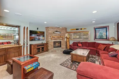a living room with a red couch and a fireplace at Lakefront Estate w Private Dock HotTub FirePit Lagunita Shores by AvantStay in Big Bear Lake