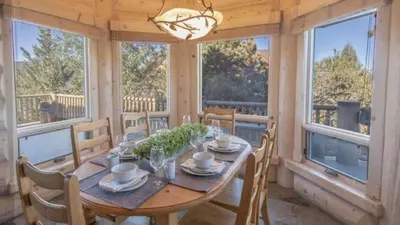a dining room with a table and chairs and windows at Hot Tub Game Room Large Deck w Incredible View Penticton Lodge by AvantStay in Big Bear Lake