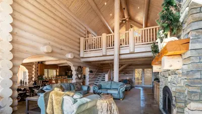 a living room with a staircase and a stone fireplace at Hot Tub Game Room Large Deck w Incredible View Penticton Lodge by AvantStay in Big Bear Lake