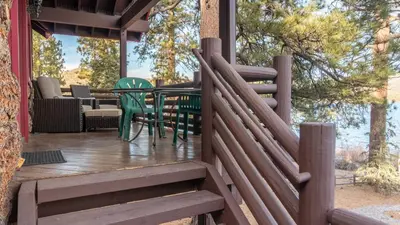 a wooden deck with a table and chairs on it at Shoreline Lakehouse by AvantStay Majestic Lakefront Cabin w Hot Tub Fire Pit in Big Bear Lake