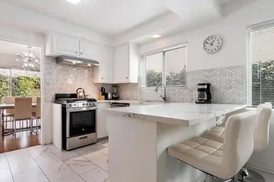 a kitchen with white cabinets and a clock on the wall at Modern spacious home close to Universal studio & Hollywood for 11 in Los Angeles