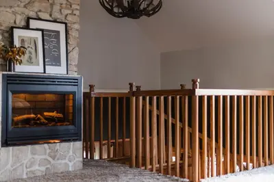 a living room with a fireplace and a staircase at Walk to the Lake Sand Volleyball Court Pool Table Deck Gambler by AvantStay in Big Bear Lake