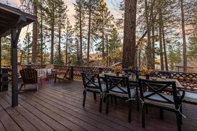 a table and chairs on a deck with trees at Walk to the Lake Sand Volleyball Court Pool Table Deck Gambler by AvantStay in Big Bear Lake