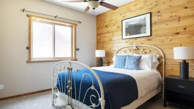 a bedroom with a bed with a wooden wall at Bernard by AvantStay Luxurious Cabin in Big Bear w Hot Tub Pool Table in Big Bear Lake