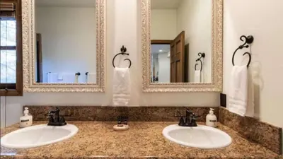 two sinks in a bathroom with two mirrors at Big Bear Castle by AvantStay Private Home in Great Big Bear Location w Hot Tub in Big Bear Lake