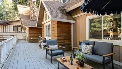 a deck with chairs and tables on a house at Hartwood by AvantStay Cozy Big Bear Abode w Spacious Deck Stone Fireplace in Big Bear Lake