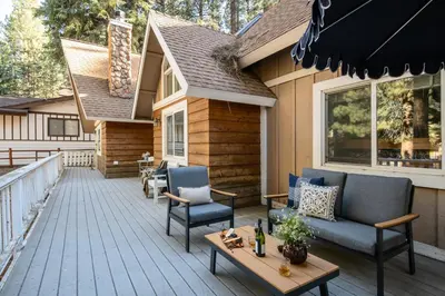 a deck with chairs and a table on a house at Hartwood by AvantStay Cozy Big Bear Abode w Spacious Deck Stone Fireplace in Big Bear Lake