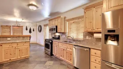a large kitchen with wooden cabinets and stainless steel appliances at Starlight Retreat by AvantStay Gorgeous Log Style Home w Incredible Views in Big Bear Lake