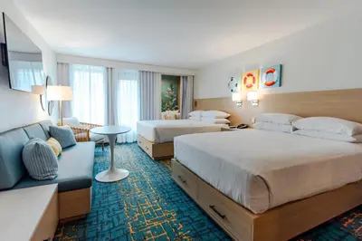 a hotel room with two beds and a couch at Howard Johnson by Wyndham Anaheim Hotel and Water Playground in Anaheim