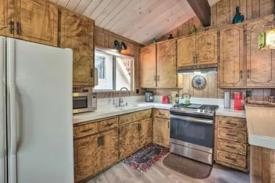a kitchen with wooden cabinets and a refrigerator at Lake Arrowhead Cabin with Mid-Century Charm! in Lake Arrowhead
