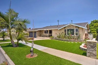 a house with a palm tree in a yard at Quiet Anaheim Home with Pool, 5 Mi to Disney! in Anaheim