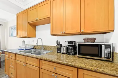a kitchen with wooden cabinets and a microwave and a sink at Bright & Cozy Getaway-10min to Downtown LA in Alhambra