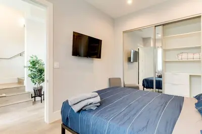 a bedroom with a bed and a tv on a wall at 2 Luxury Modern 8 Bedroom Home with Rooftop Decks in Los Angeles