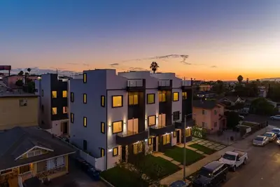a building in a city with the sunset in the background at 2 Luxury Modern 8 Bedroom Home with Rooftop Decks in Los Angeles