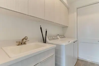 a white kitchen with a sink and a washing machine at 2 Luxury Modern 8 Bedroom Home with Rooftop Decks in Los Angeles