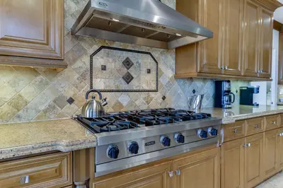 a stove top in a kitchen with wooden cabinets at Beverly Hills City View Mansion in Los Angeles