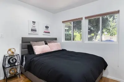 a bedroom with a black bed with two windows at 4 Bedroom house large pool & spa in prime location in Los Angeles