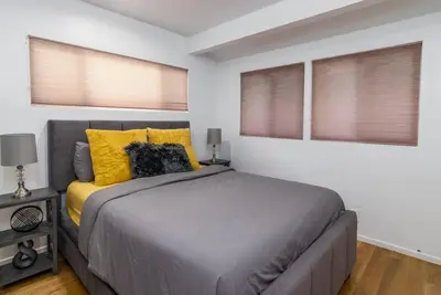 a bedroom with a bed with yellow pillows and windows at 4 Bedroom house large pool & spa in prime location in Los Angeles