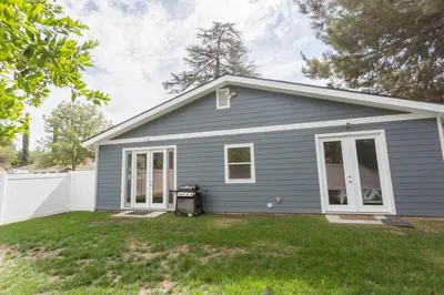 a blue house with a white fence in a yard at Lake Balboa Modern 4 Bedroom 3 Bath Glam Charmer in Raymer