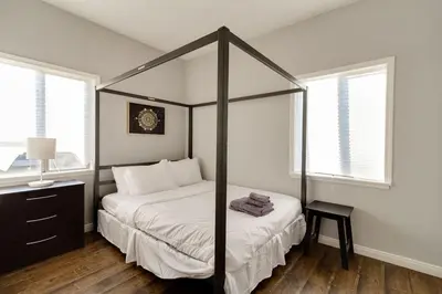 a bedroom with a canopy bed with a table and two windows at Cozy 3 bedroom San Fernando Valley in San Fernando