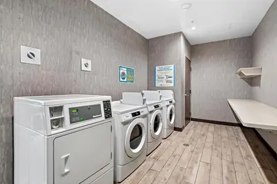 a laundry room with three washing machines and a counter at Home2 Suites By Hilton San Bernardino in San Bernardino