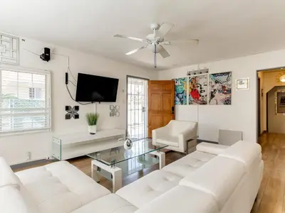 a living room with white furniture and a flat screen tv at 3 bedroom Mid-Wilshire Charmer near Downtown in Los Angeles