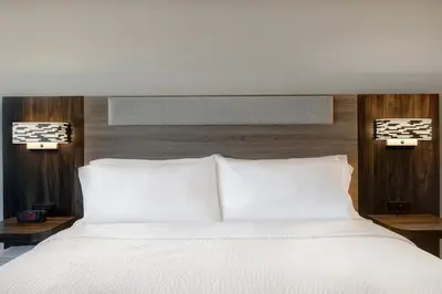 a bedroom with a bed with white sheets and wooden walls at Holiday Inn Express & Suites Ontario - Chino Hills by IHG in Chino Hills