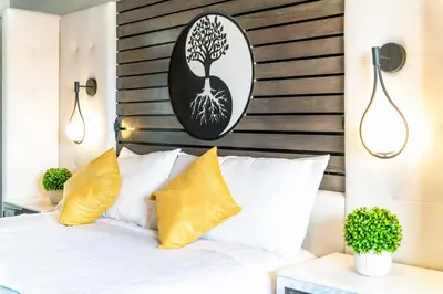 a bedroom with a white bed with a tree picture on the wall at Aspire Inn Studios & Spas in Bellflower