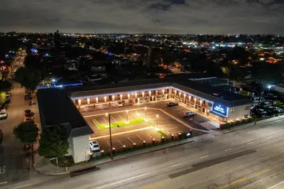 a building with a tennis court at night at Aspire Inn Studios & Spas in Bellflower