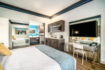 a bedroom with a large bed and a desk and a kitchen at Aspire Inn Studios & Spas in Bellflower