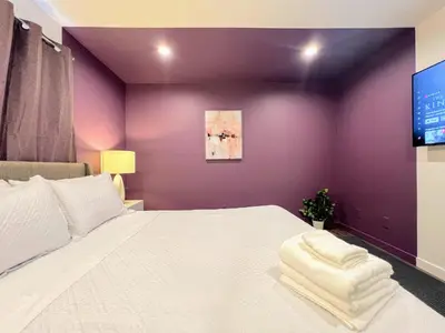 a bedroom with a white bed with a purple wall at Hollywood Purple Habitat in Los Angeles