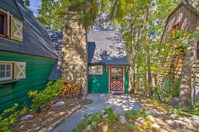 a green house with a green door and trees at Vintage Lake Arrowhead Cabin - Walk to Lake! in Lake Arrowhead