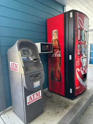 a coca cola machine next to a soda bottle at Fountain Inn Motel - Alhambra, Los Angeles in Alhambra