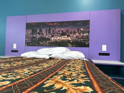 a bed in a purple room with a poster of a city at Fountain Inn Motel - Alhambra, Los Angeles in Alhambra