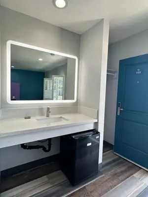 a bathroom with a sink and a mirror and a blue door at Fountain Inn Motel - Alhambra, Los Angeles in Alhambra