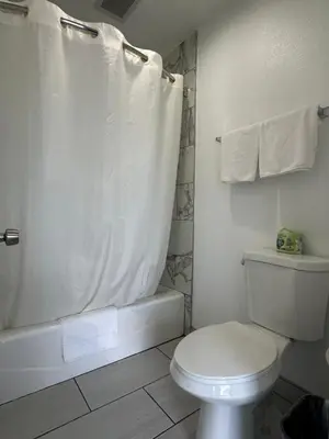 a white bathroom with a toilet and a shower at Fountain Inn Motel - Alhambra, Los Angeles in Alhambra