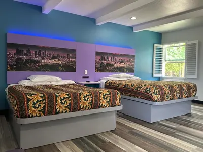 two beds in a room with blue and purple walls at Fountain Inn Motel - Alhambra, Los Angeles in Alhambra