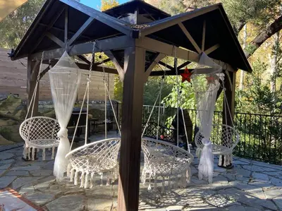 a gazebo with white chairs and a table with at Vintage RV Creekside Nature Retreat near Ojai next to Swim Holes Hike in Santa Paula