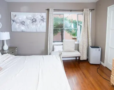 a bedroom with a bed and a chair and a window at Manuel Y Sonia-La casa de los Angeles in Long Beach