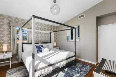 a bedroom with a canopy bed and a window at Beach Villa * Hot Tub * Steps to Beach in Long Beach