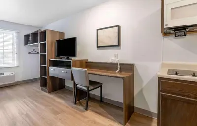 a room with a desk with a computer and a television at Extended Stay America Suites - Redlands in Redlands