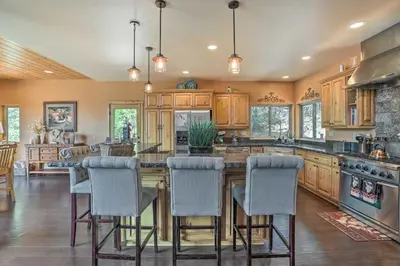 a kitchen with wooden cabinets and a large island with bar chairs at The Zen Playhouse with Lake Arrowhead Access! in Lake Arrowhead