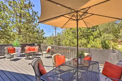 a patio with a table and chairs and an umbrella at Luxe Timberland Villa with Lake Arrowhead Access! in Lake Arrowhead