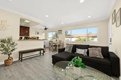 a living room with a black couch and a table at Sunny & Cheerful Near I-10 Queen Beds w Parking! in Alhambra